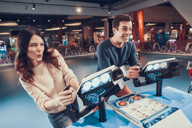 El hombre y la mujer están pilotando aviones azules jugando en una sala de juegos.