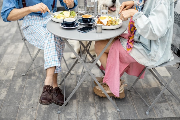 Un hombre y una mujer con estilo desayunan en un café al aire libre