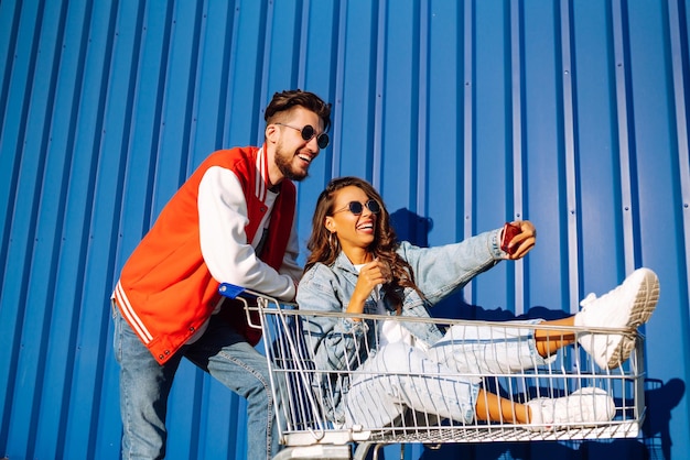 Hombre y mujer con estilo divirtiéndose y montando carrito de compras Estilo de vida ocio entretenimiento juventud