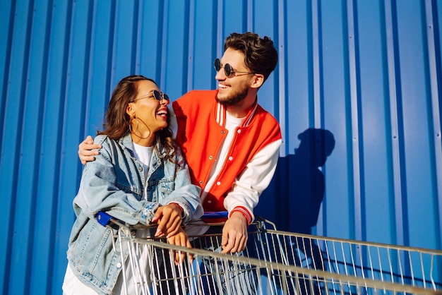 Hombre y mujer con estilo divirtiéndose y montando carrito de compras Estilo de vida ocio entretenimiento juventud