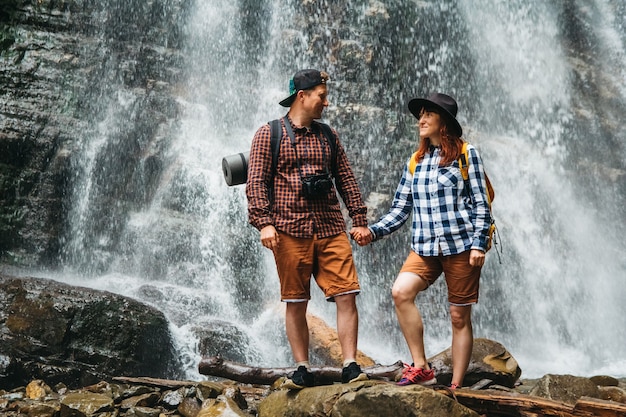 Hombre y mujer excursionistas trekking por un camino rocoso con el telón de fondo de una cascada y rocas