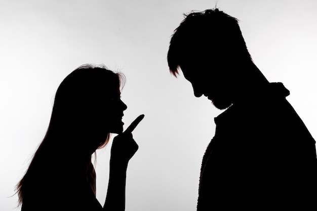 Hombre y mujer expresando violencia doméstica en silueta de estudio