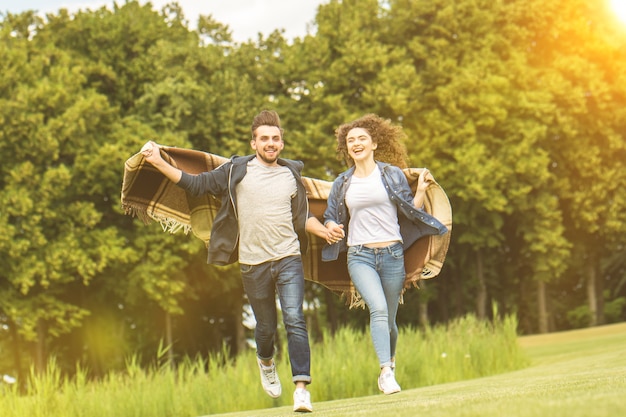 El hombre y la mujer felices corriendo sobre la hierba