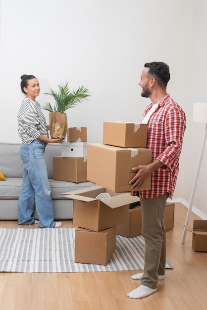 Hombre y mujer felices recogen cosas en cajas de cartón.