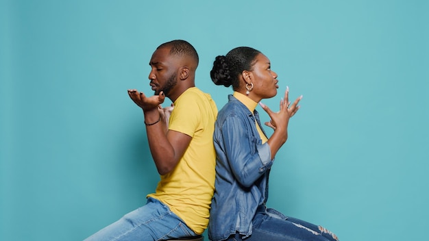 Hombre y mujer frustrados sentados espalda con espalda y discutiendo en el estudio. Pareja en conflicto peleando y discutiendo debido a problemas de relación. Personas que expresan emociones.