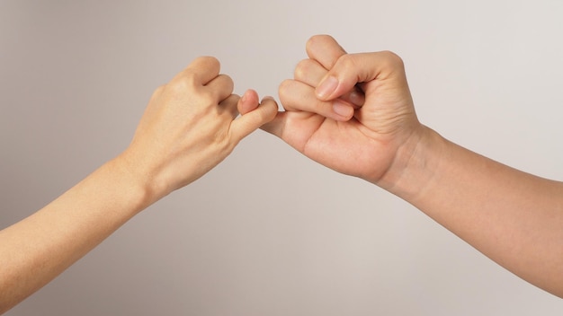 El hombre y la mujer hacen la promesa Pinky o el meñique jura las manos firman sobre fondo blanco