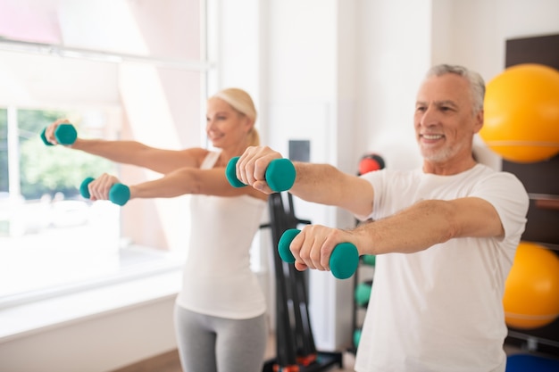 Hombre y mujer haciendo ejercicio con pesas y estirando los brazos