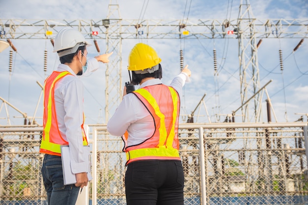 Foto el hombre y la mujer de ingeniería de comunicación permanente en el sistema eléctrico de la planta de energía