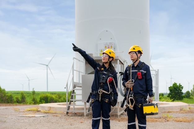 Hombre y mujer ingenieros de inspección preparando y comprobación de progreso de una turbina eólica