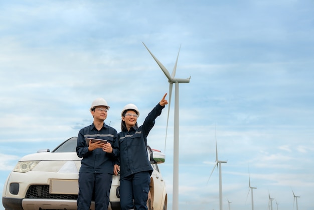 Hombre y mujer ingenieros de inspección preparando y comprobar el progreso con tableta digital de una turbina eólica