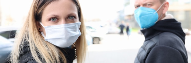 Hombre y mujer joven caminando por la calle con máscaras protectoras