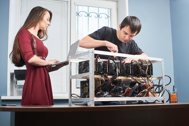 Hombre y mujer joven configurando una granja de tarjetas de video para la minería de criptomonedas