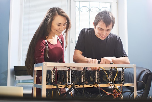 Hombre y mujer joven configurando una granja de tarjetas de video para la minería de criptomonedas