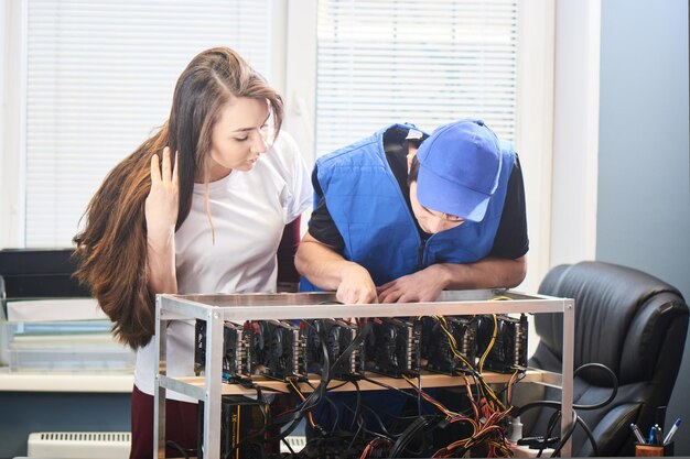 Hombre y mujer joven configurando una granja de tarjetas de video para la minería de criptomonedas