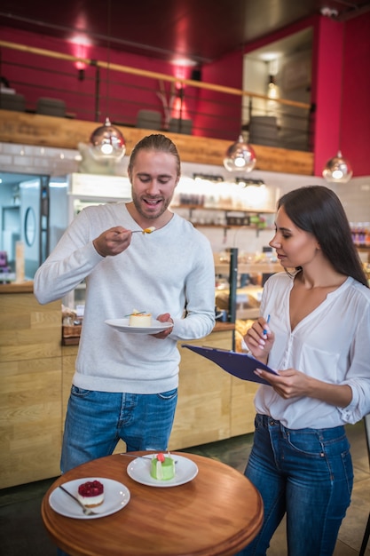 Foto hombre y mujer joven degustación de postres en un restaurante