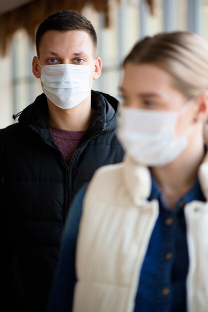 Hombre y mujer joven con máscaras médicas en un salón del aeropuerto