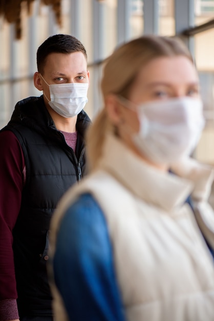 Foto hombre y mujer joven con máscaras médicas en un salón del aeropuerto