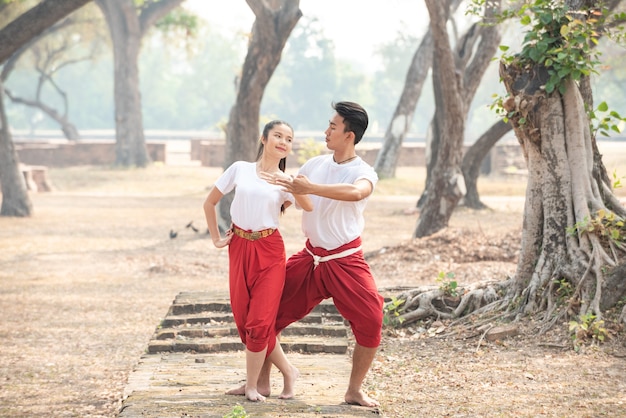 Hombre y mujer joven practicando una danza tradicional tailandesa