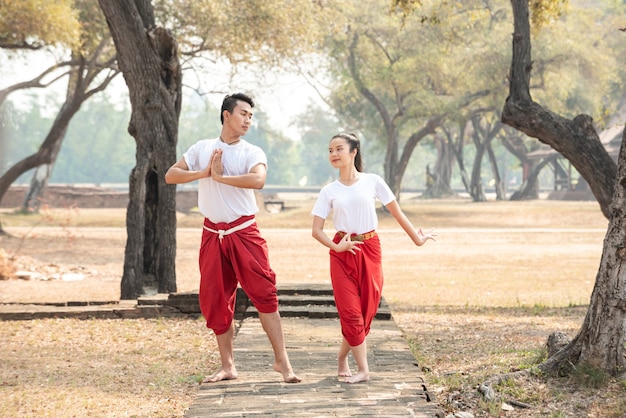 Hombre y mujer joven practicando una danza tradicional tailandesa