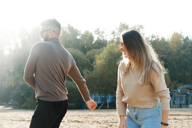 El hombre y la mujer jóvenes se divierten y bailan en la playa Clima soleado y fresco afuera