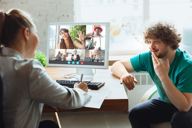 Hombre y mujer jóvenes participan en videoconferencia mirando la pantalla del portátil durante la reunión virtual, aplicación de cámara web de videollamada para negocios, de cerca. Trabajo remoto, autónomo, educación, concepto de estilo de vida.