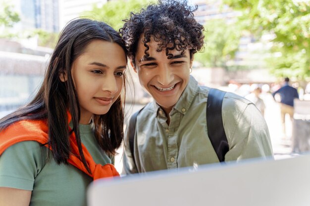 Foto un hombre y una mujer jóvenes usando un ordenador portátil aprendiendo idiomas en la calle india