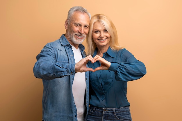 Foto hombre y mujer jubilados felices mostrando un gesto de corazón