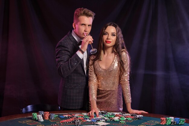 Hombre y mujer jugando al póquer en el casino celebrando la victoria en la mesa con pilas de fichas dinero tarjetas cham