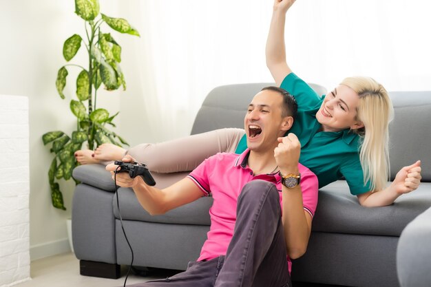 Hombre y mujer jugando videojuegos con joystick en casa.