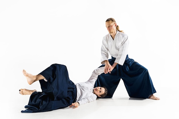 Hombre y mujer luchando y entrenando aikido en la pared blanca del estudio