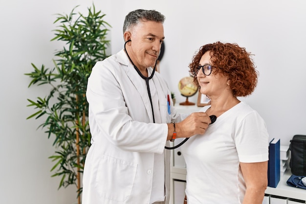 Hombre y mujer de mediana edad con uniforme médico auscultan el corazón con consulta médica en la clínica