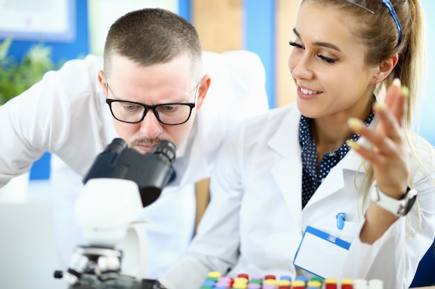 Un hombre y una mujer miran a través de un microscopio en un laboratorio químico