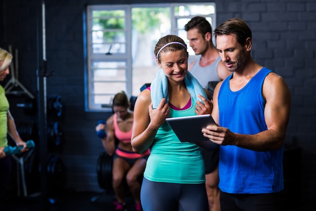 Hombre y mujer mirando en tableta en el gimnasio