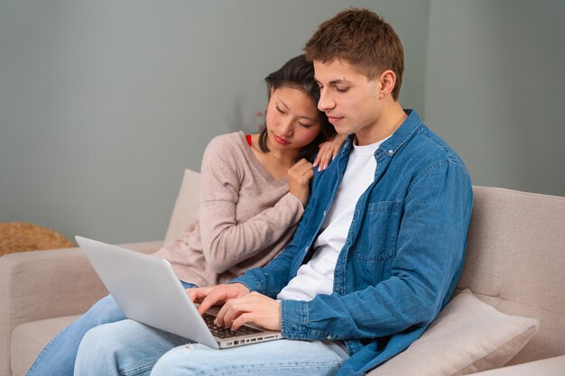 Hombre y mujer multiétnicos felices se divierten navegando por Internet en el concepto de tecnología portátil