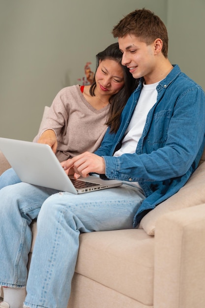 Hombre y mujer multiétnicos felices se divierten navegando por Internet en la tecnología portátil concepto vertical