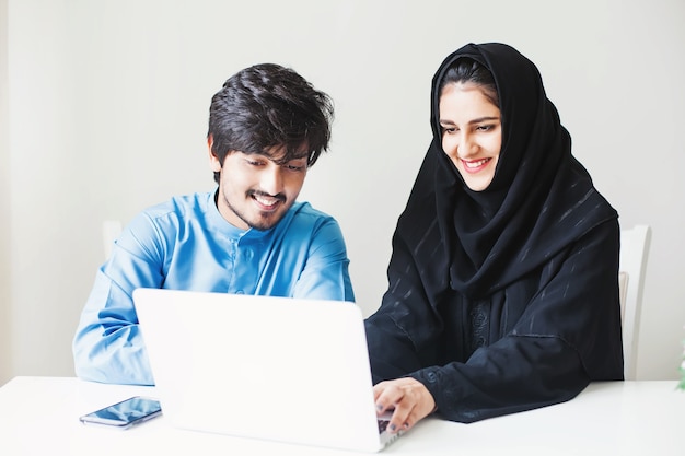 Hombre y mujer musulmana del Medio Oriente trabajando juntos en una computadora portátil