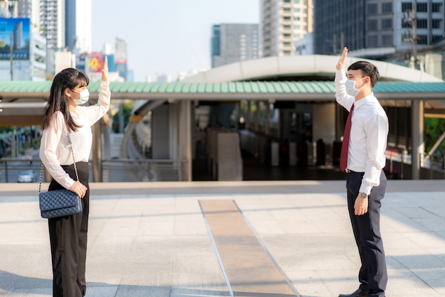 El hombre y la mujer de negocios asiáticos saludan y saludan con un colega de negocios y usan una máscara con una distancia de pie de 1 metro de distancia protegen contra los virus COVID-19