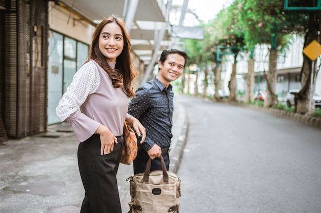 Hombre y mujer de negocios caminando a través de la acera sonriendo a la oficina