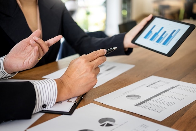 El hombre y la mujer de negocios discuten sobre el plan financiero en la tableta digital en la oficina moderna, concepto de la auditoría.