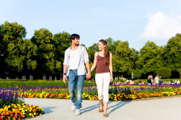 Hombre y mujer o pareja joven haciendo un viaje como turistas en el parque caminando de la mano