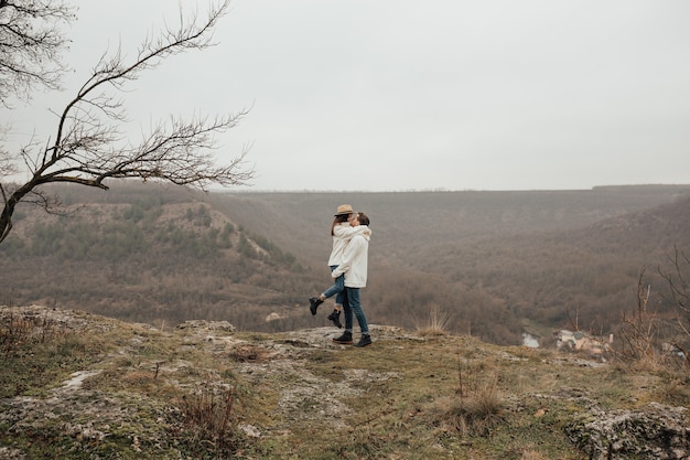 El hombre y la mujer se paran y abrazan en la cima de la montaña.