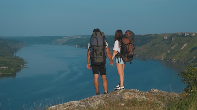 El hombre y la mujer se paran en la cima de la montaña sobre el hermoso río.