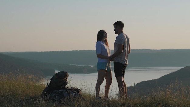 El hombre y la mujer se paran en la cima de la montaña sobre el hermoso río.