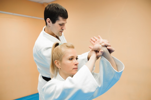 Hombre y mujer peleando en el entrenamiento de Aikido en la escuela de artes marciales