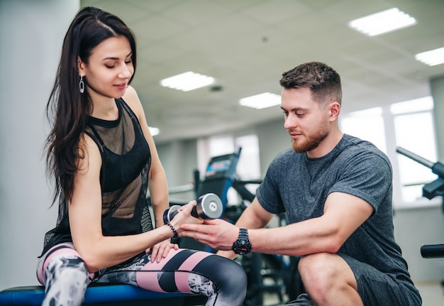 Foto hombre y mujer con pesas flexionando los músculos en el gimnasio