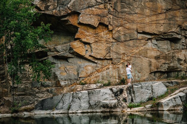 Hombre y mujer de pie y abrazos recogidos en las manos sobre la superficie de las rocas