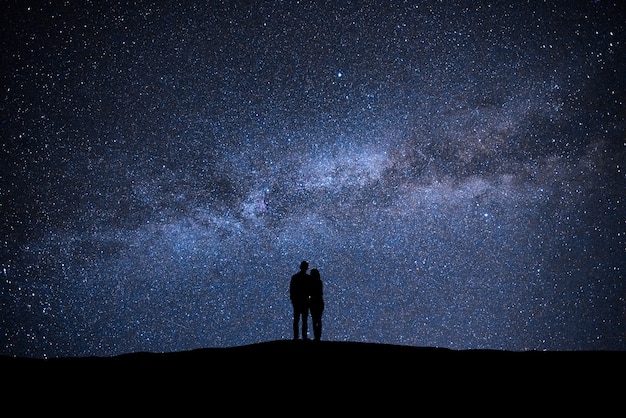 El hombre y la mujer de pie en el cielo con fondo de estrellas