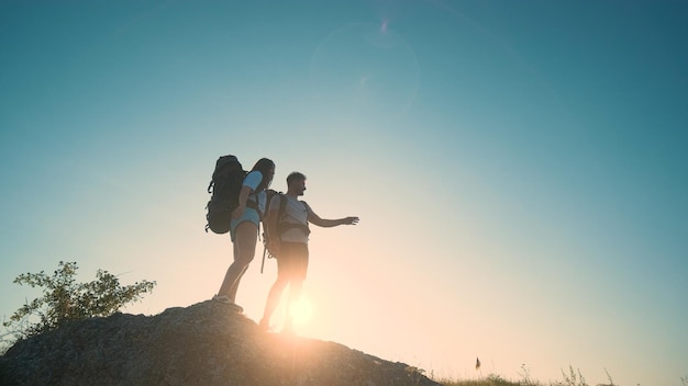 El hombre y la mujer de pie en la cima de una montaña sobre un fondo de cielo azul