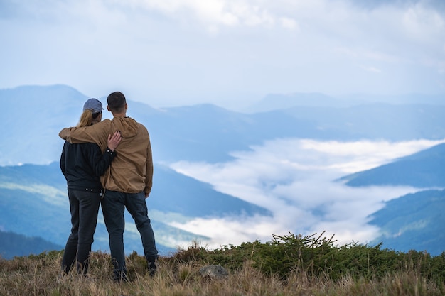 El hombre y una mujer de pie en el fondo del paisaje de montaña