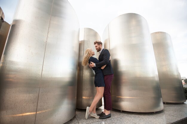 Hombre y mujer posan frente a los grandes tubos de metal